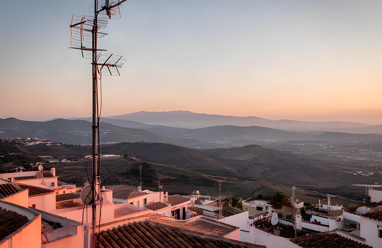 Antena de radio sobre los tejados de Vélez-Málaga al amanecer, con la Axarquía al fondo